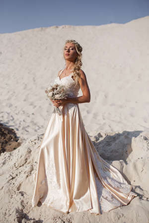 Beautiful bride is wearing fashion flying dress and wreath in the great desert in Dubai.の写真素材