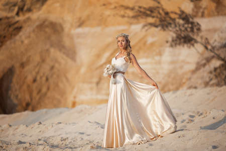 Beautiful bride is wearing fashion flying dress and wreath in the great desert in Dubai.の写真素材