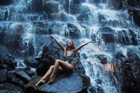 Beautiful sexy girl under Kanto Lampo waterfall in Indonesia.