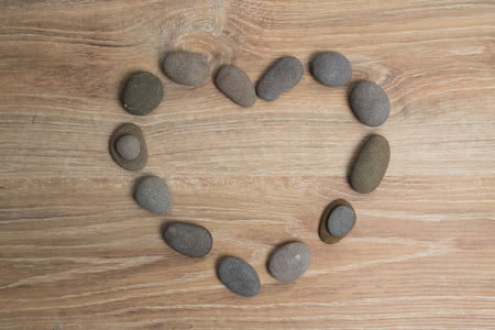 Heart lined with sea stones. River stones in the shape of a heart on a wooden background.の写真素材
