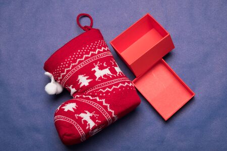 Christmas background studio image. Red gift box with christmas sock on a blue background. Greeting...