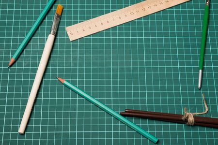 School supplies on a cutting mat. Pencils, ruler and brushes for painting.