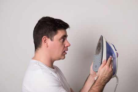 Young man burned clothes with an iron. Positive man with a broken iron.の写真素材