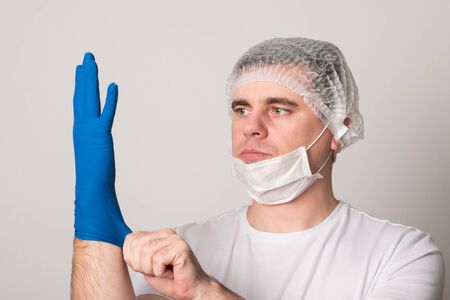 Doctor in a surgical mask, gloves and glasses. Surgeon before the operation. Young man in a medical mask.の写真素材