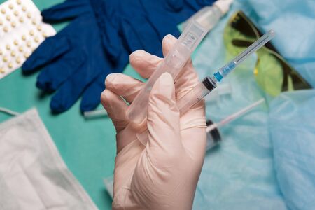 Doctor's hand holds a syringe. Hand with a syringe on a background of medical instruments.