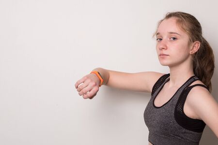 Sports young girl with fitness bracelet for sports. Teen girl in sportswear looking at fitness...