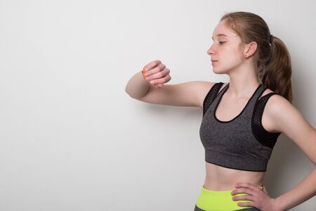 Sports young girl with fitness bracelet for sports. Teen girl in sportswear looking at fitness...