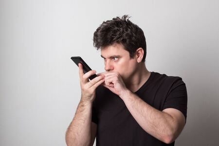 Man is talking on a cell phone. Smiling young man in a black T-shirt talking on the phone.の写真素材