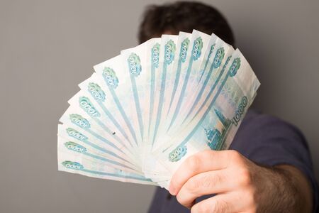 Male hand holds money. Man holds Russian rubles. Russian money, large banknotes in a hand.の写真素材