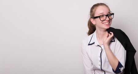 Happy girl in glasses puts on a jacket. Charming caucasian girl in glasses. Banner with an empty space for text.の写真素材