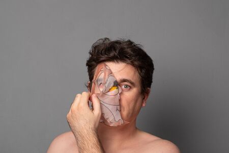 Man in a cosmetic mask. Funny man with facial masks having fun on studio. Facial mask of man. Man on spa procedure. Anti-aging cosmetic mask.の写真素材