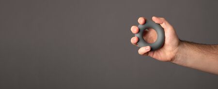 Male hand holds an expander. Expander in a male hand. Banner with space for text.の写真素材