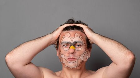 Man in a cosmetic mask. Funny man with facial masks having fun on studio. Facial mask of man. Man on spa procedure. Anti-aging cosmetic mask.の写真素材