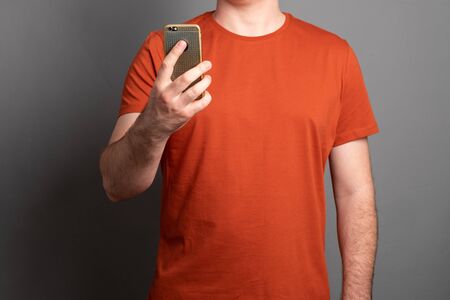 Man holds a mobile phone. Man takes a selfie on a cell phone.