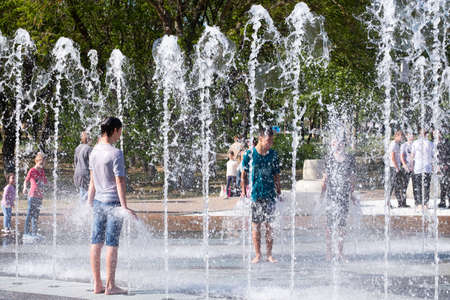 Kerch/Russia - May 31, 2020: Happy cheerful teens swimming in the fountain. Children laugh and splash in fountain in the summer park.のeditorial素材