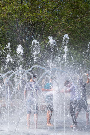 Kerch/Russia - May 31, 2020: Happy children laugh and splash in fountain in the summer park. People walk in the summer park.のeditorial素材