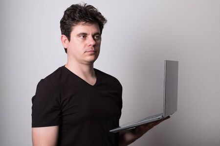 Man works at a laptop. Young man works at a computer.