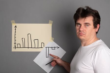 Sad man draws a graph with a drop down. Schedule of economic decline. Financial chart goes down.の写真素材