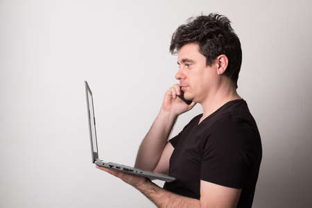 Happy man talking on a cell phone and laptop.
