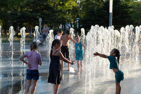 Kerch/Russia - June 27, 2020: Happy children laugh and splash in fountain in the summer park. People walk in the summer park.のeditorial素材