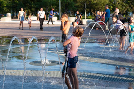 Kerch/Russia - June 27, 2020: Happy children laugh and splash in fountain in the summer park. People walk in the summer park.のeditorial素材
