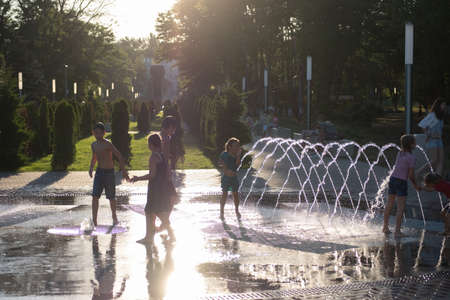 Kerch/Russia - June 27, 2020: Happy children laugh and splash in fountain in the summer park. People walk in the summer park.のeditorial素材