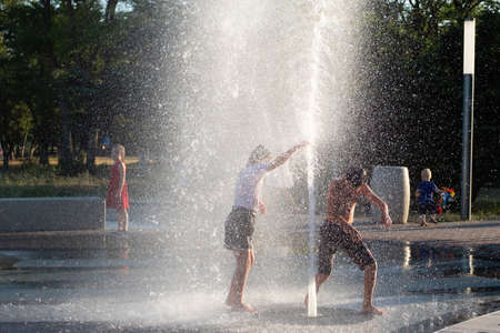 Kerch/Russia - June 27, 2020: Happy children laugh and splash in fountain in the summer park. People walk in the summer park.のeditorial素材