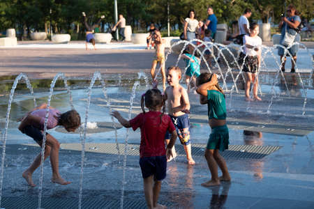 Kerch/Russia - June 27, 2020: Happy children laugh and splash in fountain in the summer park. People walk in the summer park.のeditorial素材