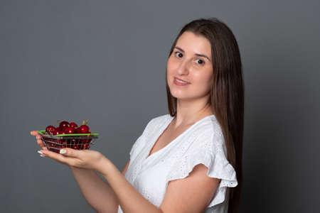 Beautiful woman is holding ripe red berries. Young woman eats sweet cherries.