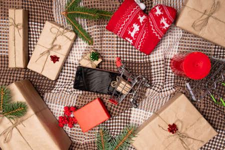 Christmas online shopping with phone. Online shopping concept - full Shopping Cart and gift box.screen of smartphone with copy space.の写真素材