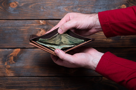 Wallet with dollars in men's hands. Wallet with money on a wooden background.の写真素材