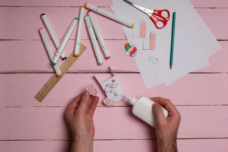 Step 10. DIY Children's Easter craft bunny with an egg. Easter craft paper step by step instructions happy bunny holds egg.の写真素材