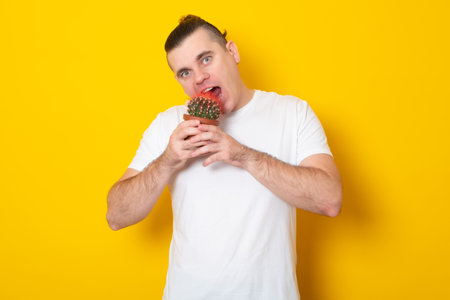 Concept with a young man in T-shirt, holding in hand a cactus suggesting pain, bites a cactusの写真素材