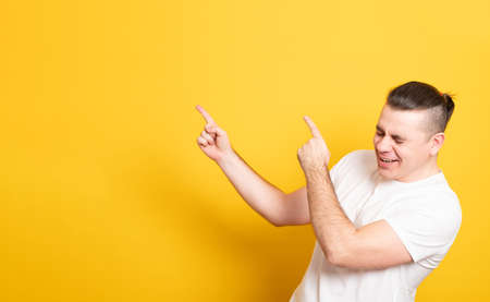 Laughing young man pointing away at copy space with two fingers. Banner copy spase.