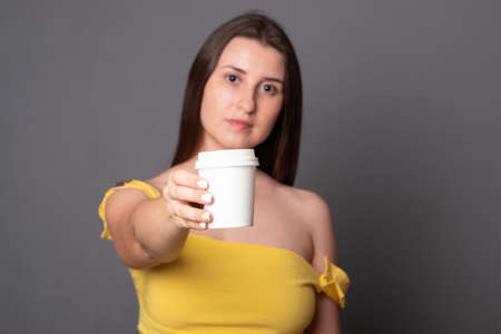 Young woman holding a paper cup with place for text.の写真素材