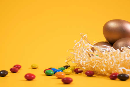 Easter background with colorful eggs in nest on a yellow background. Top view with copy space. Banner.の写真素材