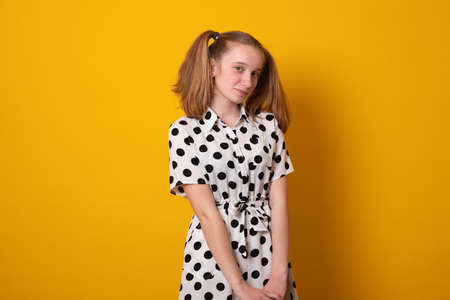 Cute girl with a two-ponytail hairstyle smiles with braces on a yellow background. Teenager girl with a cheerful hairstyle from two ponytails.の写真素材