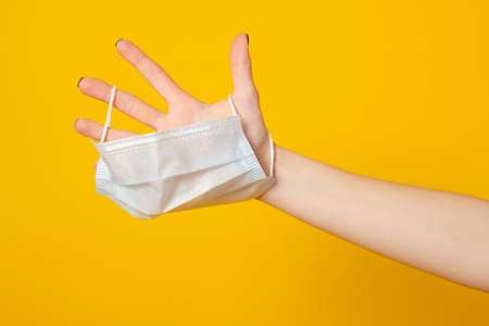 Female hand holds a medical mask, the concept of the end of the pandemic and mask mode.の写真素材