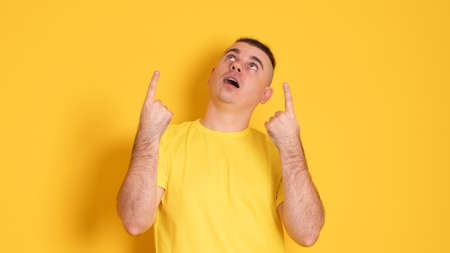 Young handsome man wearing casual t-shirt over yellow background pointing fingers up with successful idea. Exited and happy. Number one.の写真素材