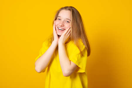 Studio portrait of a smiling teenage girl on a yellow background.の写真素材