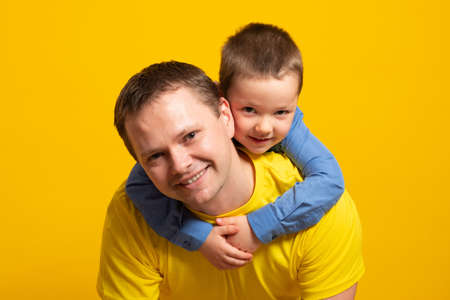 Happy father's day! Emotional dad and son hugging on yellow background.の写真素材