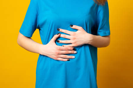 Female holding her stomach and frowns. Woman has a stomach ache. Female writhes in pain.