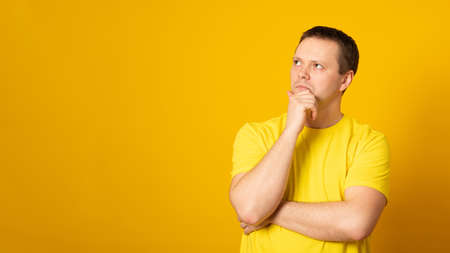 Banner. Young handsome man wearing casual t-shirt over yellow background Thinking worried about a question, concerned and nervous with hand on chin.の写真素材