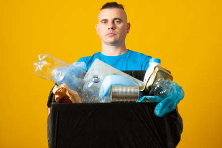 Contamination and ecological problems concept. Man holds bags with litter, picks rubbish, cleans up environment.の写真素材