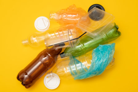 Heap of plastic disposable packaging and disposable tableware on yellow background. Concept of zero pollution and eco-friendly.の写真素材