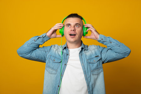 Young man listening to music using headphones looking positive and happy standing and smiling with a...