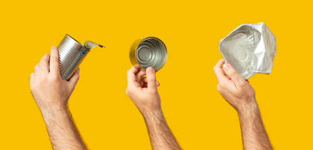 Hands holding tin can isolated on yellow background. Recycling, reuse, garbage disposal, resources environment and ecology concept.の写真素材