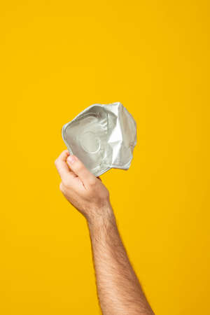 Hands hold recycling used cans, metal objects isolated on yellow background. Stop nature garbage,...