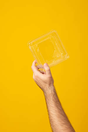 We are against plastic garbage. Hand clutches an disposable plastic box. Separation of waste,...