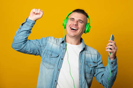 Young man listening to music using headphones looking positive and happy standing and smiling with a confident smile.の写真素材